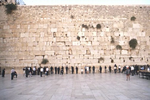 De bidder bij de Westelijke (Klaag)muur staat met de rug naar Golgotha, waar Jezus Christus buiten de muren van de stad ieder mens aanklaagde.